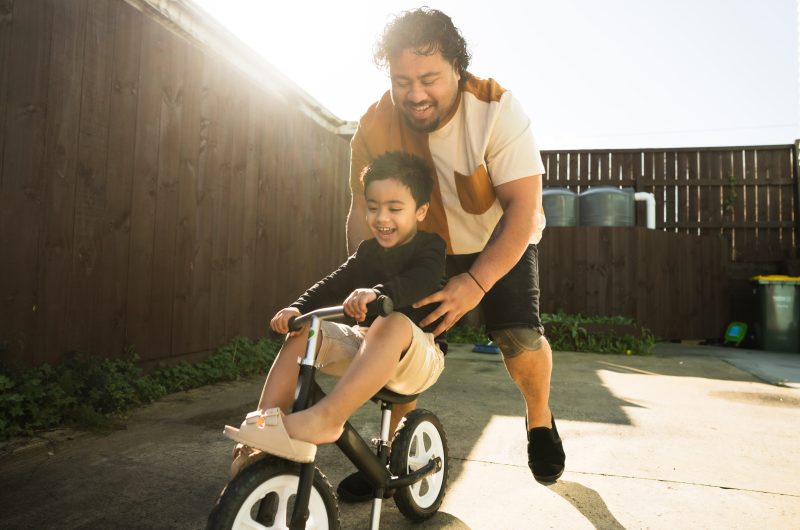 Pacific Islander father teaching his cute little son to ride bicycle, active lifestyles concept.